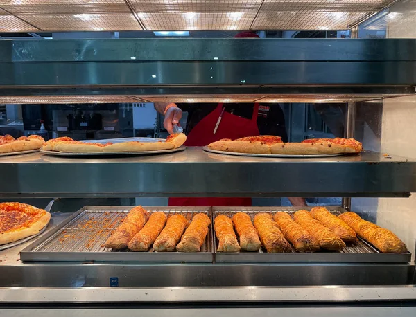 Signal Hill, CA USA - 20 Ocak 2021: Tepsiden pepperoni pizzasını alan bir çalışanla Costco yemek salonunun yakın görüntüsü