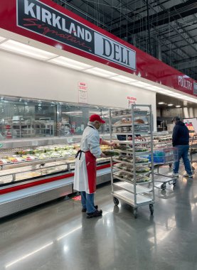 McKinney, TX USA - 22 Şubat 2021: Costco Deli çalışanı şarküteri tabağını rafa dolduruyor