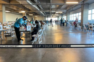 Frisco TX, USA - March 26, 2021: Indoor view of people wearing mask and filling up the COVID 19 vaccination form