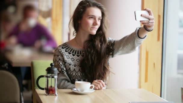 Chica joven hace selfie en un café después de té de frutas — Vídeo de stock