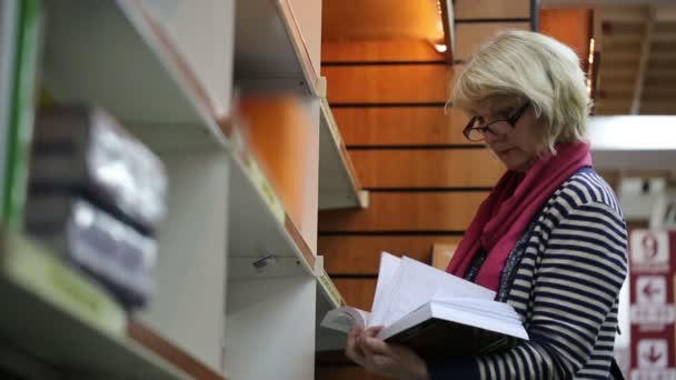 Mulher loira que navega livros em uma livraria — Vídeo de Stock