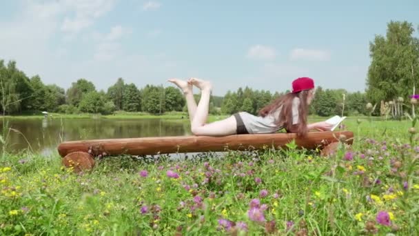 Jong meisje liggend op een bankje en lezen van een boek 4. — Stockvideo
