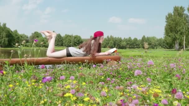 Young girl lying on a bench and reading a book 5. — Stock Video