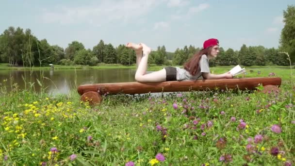 Young girl lying on a bench and reading a book 2. — Stock Video