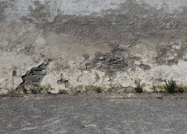 Eski, yıpranmış dış duvar, ağır hasarlı alçı ve duvarla kaplı. Yaşlanma, nem ve çürüme belirtileri var. Üs boyunca yosun ve küçük bitkiler büyüyor, bu da uzun süreli ihmalin göstergesi. Bir doku ya da arkaplan kadar mükemmel 