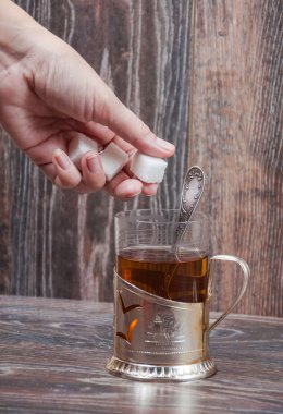 El bir parça şeker bir bardak çay atar.