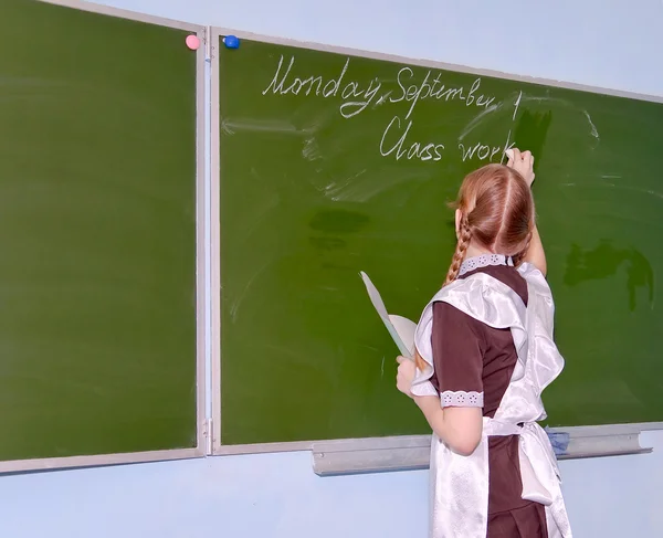 Ein Schulmädchen schreibt auf die Tafel — Stockfoto