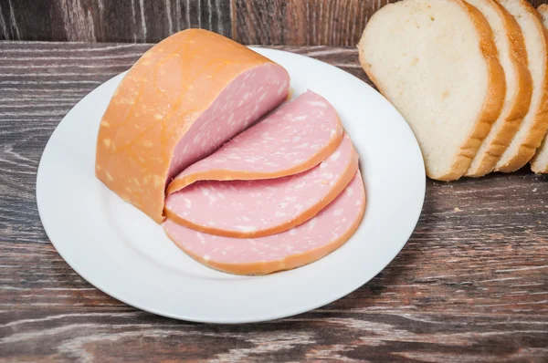 Sliced cooked sausage and a loaf of white bread — Stock Photo, Image