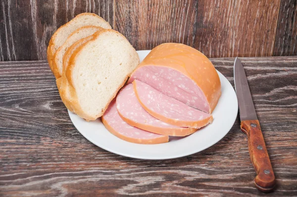 Nakrájené vařené klobásy a bochník bílého chleba — Stock fotografie