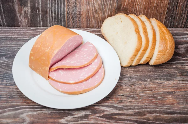 Sliced cooked sausage and a loaf of white bread — Stock Photo, Image