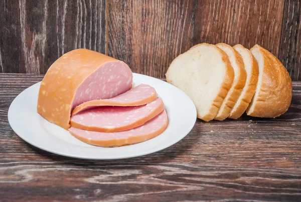 Sliced cooked sausage and a loaf of white bread — Stock Photo, Image