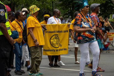 Kanada, 05 Temmuz 2025: Yaşlılar renkli halk caddesi geçit töreninde sancakla gururla yürüyorlar.