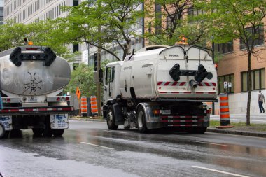 Quebec, Kanada, 05 Temmuz 2025: Sokak temizleyicileri ve kamu araçları yağmurlu bir şehir sabahında çalışıyorlar