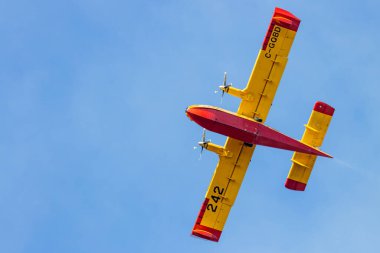 Kanada, 17 Ekim 2025: Sarı ve kırmızı itfaiye uçakları açık mavi gökyüzünde uçuyor