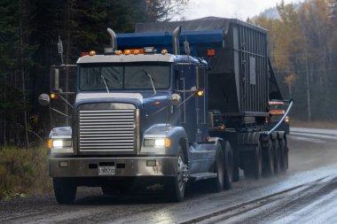 Kanada, 08 Ekim 2025: Büyük mavi kamyon çamurlu bir orman yolunda kargo taşıyor