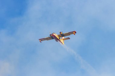 Kanada, 17 Ekim 2025: İtfaiye uçağı görev sırasında dumanlı mavi gökyüzüne su salıyor