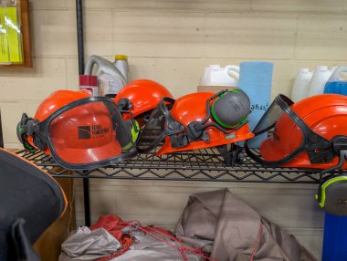 Kanada, 31 Ekim 2025: Parlak turuncu orman kaskları endüstriyel atölye rafında düzgün bir şekilde hizalandılar