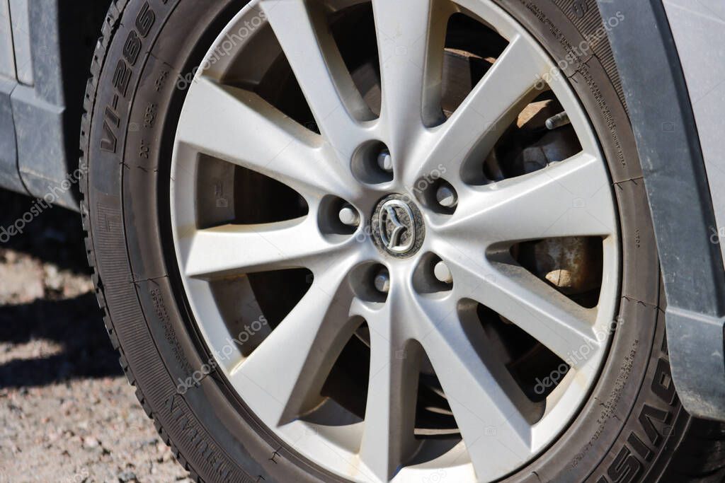 Canada, 27 September 2025 : Silver alloy wheel sunlit with mazda logo on urban pavement