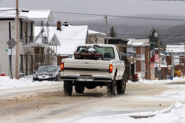 Kanada, 10 Kasım 2025: Küçük bir kasabadaki karlı kış sokağından geçen eski beyaz pikap