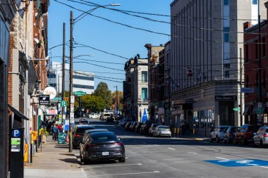 Kanada, 11 Ekim 2025: Yayalar ve işyerleriyle dolu canlı kentsel cadde boyunca park edilmiş arabalar.