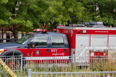 Quebec, Kanada, 05 Temmuz 2025: Montreal acil müdahale sahnesinde yeşil ağaçların yakınına park edilmiş itfaiye aracı