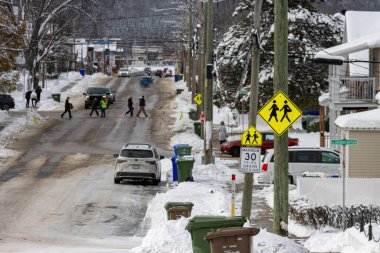 Kanada, 12 Kasım 2025: Karlı kış sokağı yaya geçitleri, araçlar, tabelalar, evler, çöpler