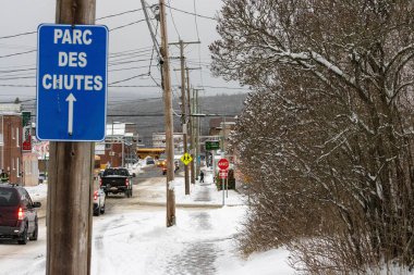 Kanada, 10 Kasım 2025: Karlı cadde trafiğin, yayaların ve kış ağaçlarının ortasındaki parka doğru ilerliyor