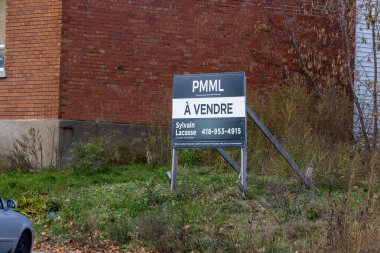 Kanada, 08 Kasım 2025 tuğla duvar arkaplanı, emlak satışı tabelası, aşırı büyümüş çimenler, sonbahar ayarı