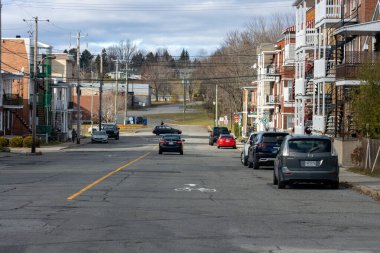 Kanada, 08 Kasım 2025: Park etmiş arabalarla sakin bir banliyö caddesi, bisikletçi şeridi, bulutlu bir gökyüzü.