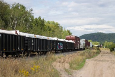 Kanada, 07 Eylül 2025: Yük treni kırsal alanlarda ağaçlar ve tepelerle seyahat ediyor