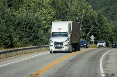 Kanada, 14 Ağustos 2025: Kavisli kırsal orman otoyolu boyunca giden büyük beyaz kamyonet