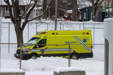 Kanada, 15 Kasım 2025: Soğuk kış günü karlı çitlerin yanına park edilmiş sarı ambulans