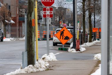 Kanada, Quebec, 27 Kasım 2025: İnşaat, dur işaretleri, arabalar ve turuncu varillerle dolu karlı şehir caddesi