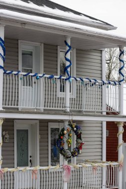 Kanada, Quebec, 27 Kasım 2025: Karlı veranda şenlikli çelenk ve mavi bayram kurdeleleriyle süslendi