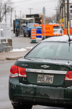 Kanada, Quebec, 27 Kasım 2025: Buzlu yeşil Chevrolet Cruze inşaat alanı turuncu uyarı levhalarının yanında