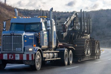 Kanada, Quebec, 08 Kasım 2025: Dağ otobanından büyük boyutta orman malzemesi taşıyan büyük mavi kamyonet
