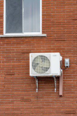 Kanada, Quebec, 27 Kasım 2025: Pencerenin altındaki tuğla duvara beyaz klima monte edildi