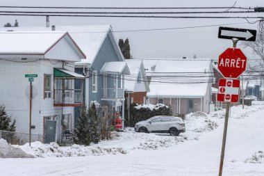 Kanada, Quebec, 30 Kasım 2025: Kar, sokak köşesini evler, arabalar, dur işareti ve kış ile kapladı.