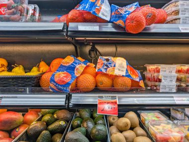 Kanada, Quebec, 29 Kasım 2025: Taze portakallar, avokadolar, kiviler, armutlar, meyve salatası kapları, canlı üretim rafları