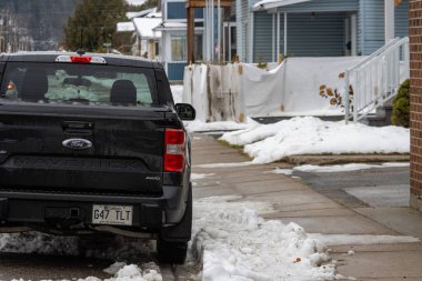 Kanada, Quebec, 27 Kasım 2025: Karlı kaldırım ve evlerin yanına park edilmiş siyah kamyonet