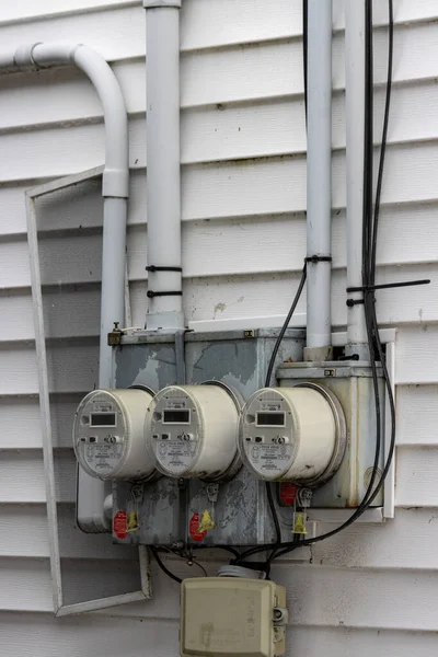 Kanada, Quebec, 27 Kasım 2025: Beyaz panelli bir evin duvarına üç adet elektrik sayacı yerleştirildi