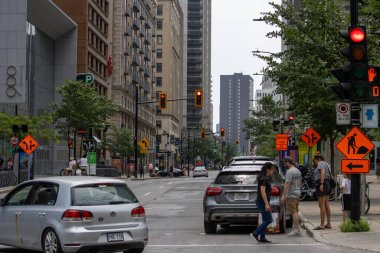 Kanada, Quebec, 06 Temmuz 2025: Yaya arabalarıyla şehir kavşağı inşaat tabelaları ağaçlar ve trafik ışıkları