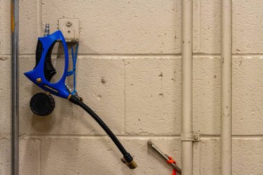 Kanada, Quebec, 03 Aralık 2025: Mavi püskürtme hortumu yakınındaki borularla beton duvarda asılı