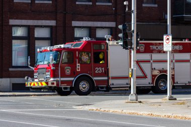 Kanada, Quebec, 11 Ekim 2025: Sessiz şehir caddesinde tuğla binanın yakınına park edilmiş kırmızı itfaiye aracı