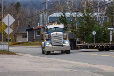 Kanada, Quebec, 29 Ekim 2025: Mavi kamyonet sakin bir banliyö sokağına sonbahar sabahı giriyor