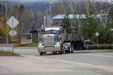 Kanada, Quebec, 29 Ekim 2025: Büyük mavi kamyonet sessiz kırsal yoldan dönüyor