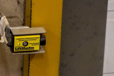 Kanada, Quebec, 03 Aralık 2025: Sarı endüstriyel sensör güvenlik kapısı tespit sistemi için sütunlara monte edildi