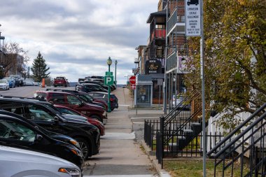 Kanada, Quebec, 08 Kasım 2025: Bulutlu öğleden sonra arabaları park halindeki cadde işletmeleri kaldırımları işaret ediyor