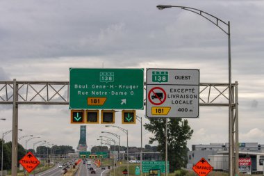 Kanada, Quebec, 20 Temmuz 2025: Trafik işaretleri, inşaat uyarısı, bulutlu gökyüzü, otoyol, şehir manzarası, yön okları