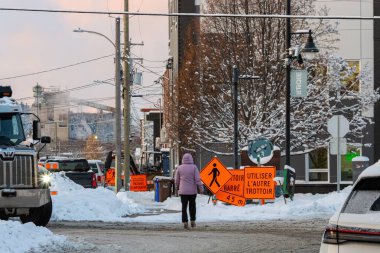 Kanada, Quebec, 11 Kasım 2025: Yayalar, inşaat işaretleri, kamyonlar ve kış ağaçlarıyla kaplı cadde